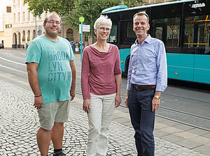 Das dreiköpfige Sprecherteam des Frankfurter Fahrgastbeirats in der Wahlperiode bis 2030 Dennis Bichiou, Dr. Kristine Schaal und Kai Werner posieren vor einem Linienbus am Südbahnhof.