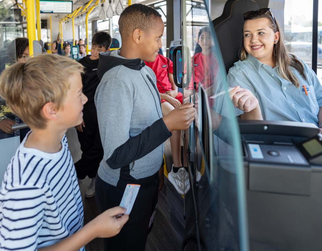 (c) traffiQ; Foto: Anja Jahn Zwei Kinder kaufen einer Fahrkarte bei einer Busfahrerin